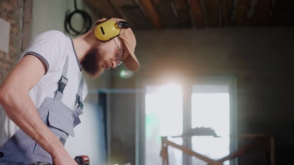 Male Builder Using Electrical Screwdriver in Construction Studio