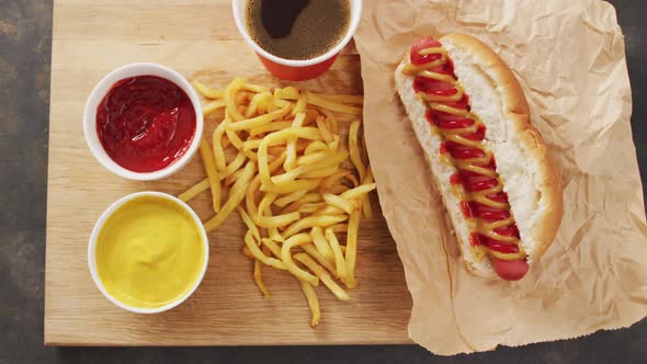 Video of hot dog with mustard, ketchup and chips on a black surface