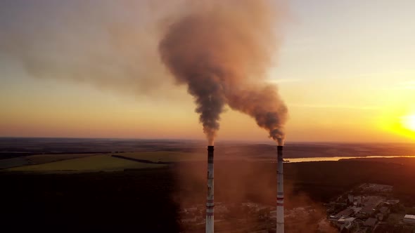 City air pollution. Plant and chimney stack with smoke and dirty orange air as illustration