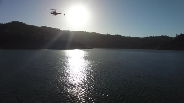 A helicopter circles above a pristine mountain lake.