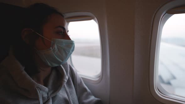 Woman Sits at Aircraft Window and Wear Medical Safety Mask in Airplane Cabin