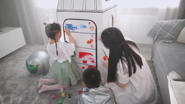 An Asian Female with Kids Play in the Living Room at Home a Boy in an Astronaut Costume Sitting on