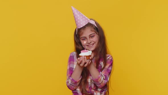 Happy Child Girl Kid Celebrating Birthday Party Makes Wish Blowing Burning Candle on Small Cupcake