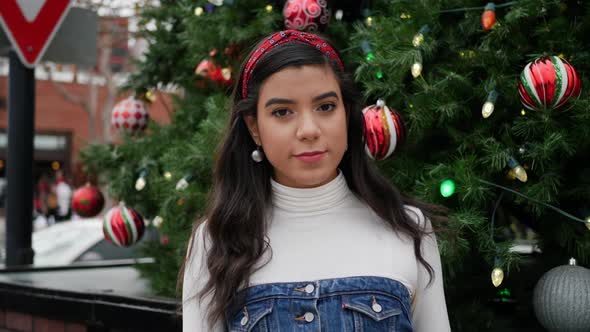 Young woman out Christmas shopping in the city with a tree decorated with ornaments and festive holi