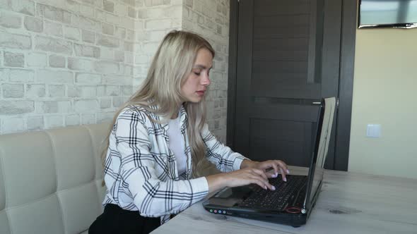 Woman Works Behind Laptop in Kitchen