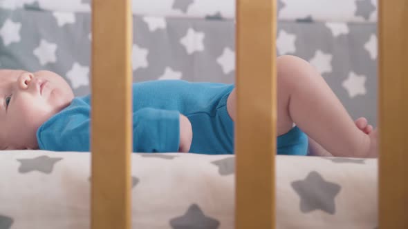 Worried Child Cries Kicking Legs and Dummy in Modern Cot