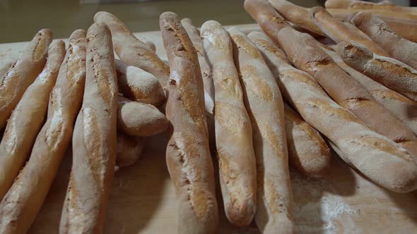 Fresh Baked Long Baguette Breads Lie on the Wooden Table Sprinkled with Flour in a Pile