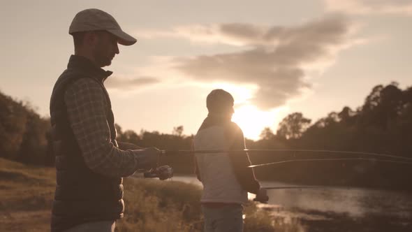 Fishermen friends with a spinning rod catching fish on a river.