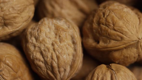 Cinematic, rotating shot of walnuts in their shells on a white surface