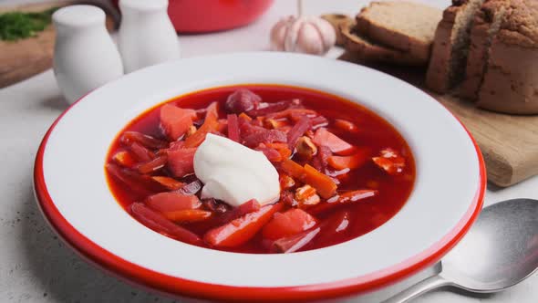 Eating beetroot soup borsch with sour cream, dill and bread with a spoon.