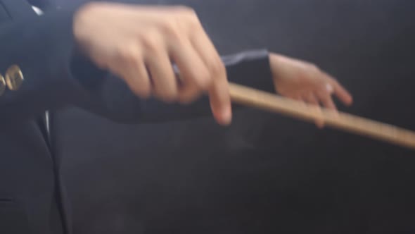 Close Up Of Side View Conductor's Hands Holding A Baton And Moving In The Black Studio