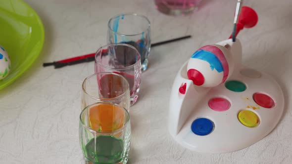 View of a boy learning to paint Easter eggs with special utensils.