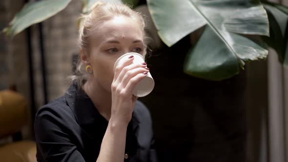 Handheld Close Up of Blonde Woman with Hair in a Bun Drinking Wine