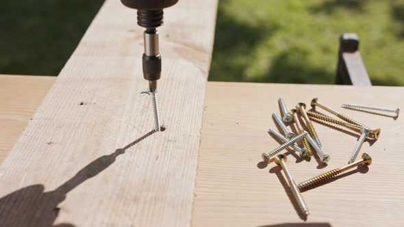 Slow motion of a man using an electric screwdriver to drive a screw into wood