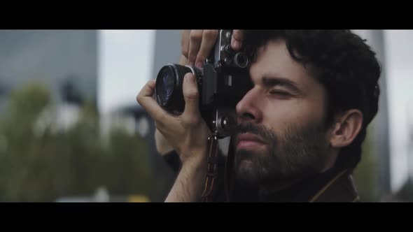 Caucasian man with beard focus,ing with his camera and taking pictures