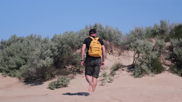 Barefoot Man with Backpack Hiking in Beautiful Coastal Sand Dune Towards Beach