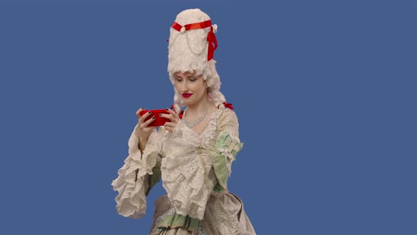 Portrait of Courtier Lady in White Vintage Lace Dress and Wig Plays Game on Smartphone and Wins