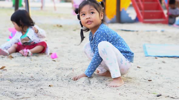 The little Asian girl is playing the sand on the playground