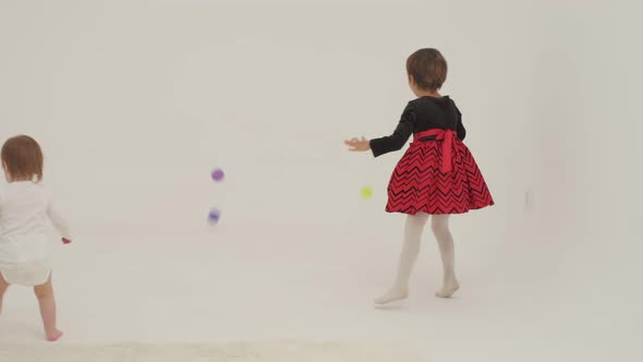 Toddler Girl Wearing Diaper and Her Sister Playing with Balls