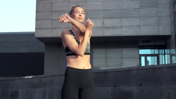 Woman Runner Stretching Arms Before Exercising Summer Morning Urban Background