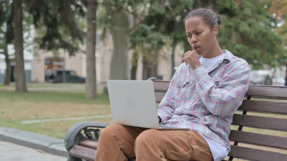 Coughing African Woman Using Laptop While Sitting Outdoor on Bench