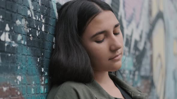 Young Hipster Brunette Girl Posing Near the Wall with Graffiti