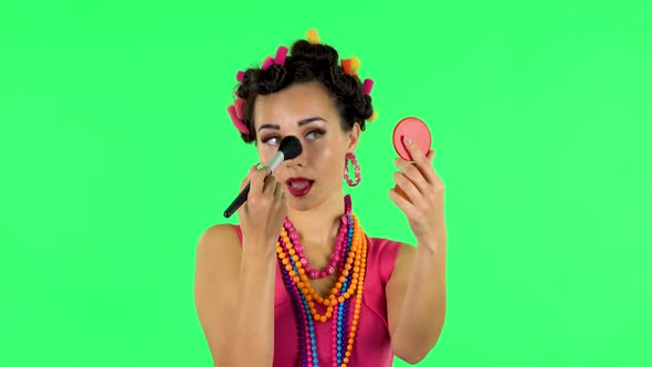 Girl with Curlers on Her Head in a Pink Dress Looking in Red Mirror and Powdered Her Nose with Big