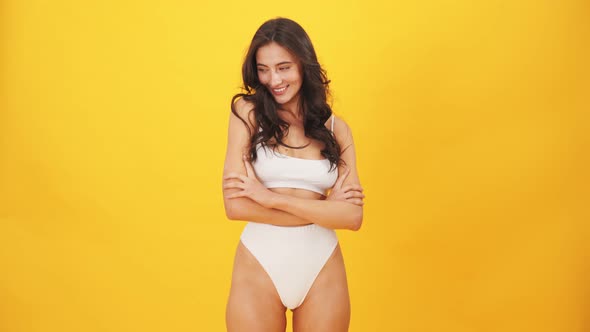 A smiling brunette woman wearing swimsuit laughing to the camera