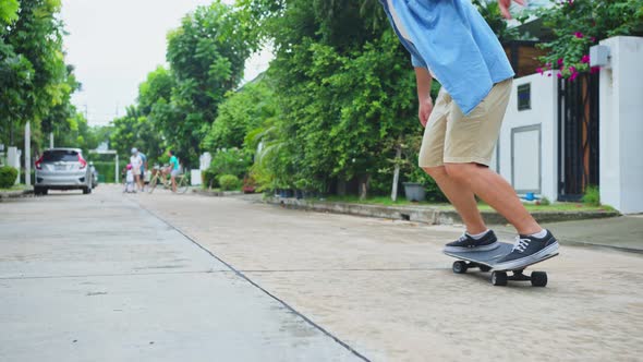 Close up active Asian hipster guy ride Surf Skate Board on street in front of his house feel enjoy.