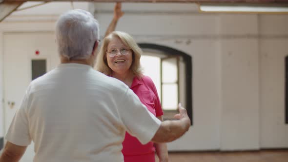 Medium Shot of Pretty Senior Couple Dancing Together in Ballroom