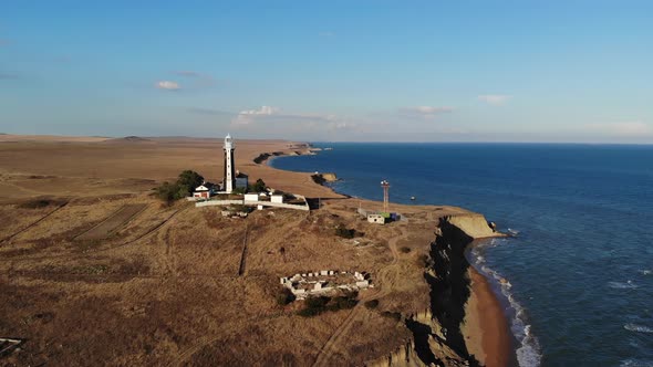 Aerial View of a Lonely Lighthouse Surrounded By Technical Buildings Stands on a Deserted Rocky