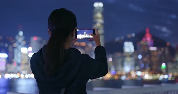 Woman take photo on cellphone in city at night