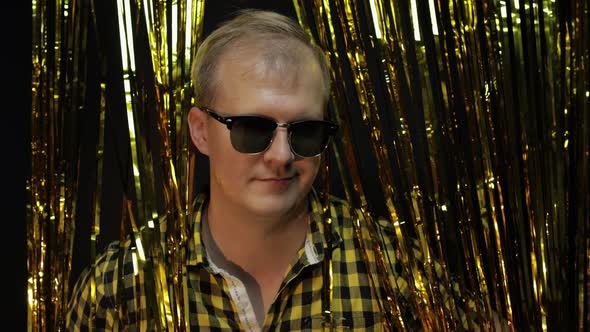 Portrait of Caucasian Man Posing on Black Background. Gold Shining Foil Strips. Party, Music, Disco