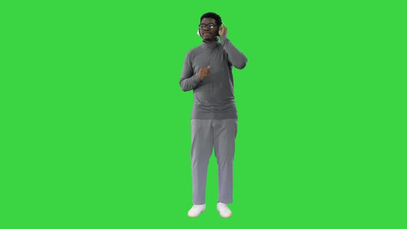 Smiling African American Man in Headphones and Moving To the Music Rhythm on a Green Screen, Chroma