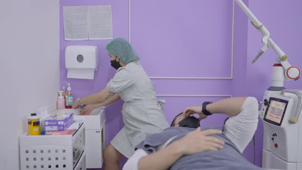 Asian Cosmetologist Wash Hands for Hygiene Before Cosmetic Procedure on Man