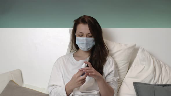 Scared Girl Protective Mask, Pajamas in Bed at Home Spraying Antiseptic on Hand