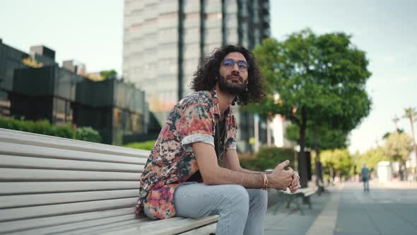 Handsome curly-haired bearded man in eyeglasses looking around