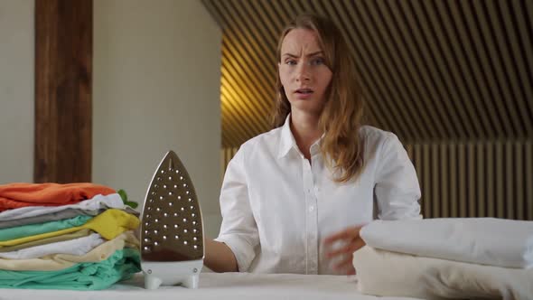 Frustrated Angry Young Woman Holding Her Head and Screaming Near the Ironing Board at Home