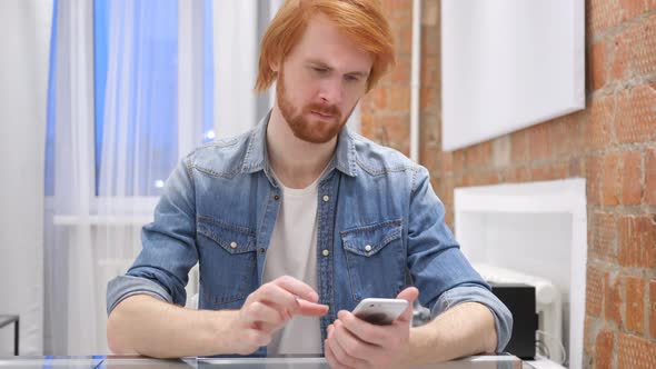 Redhead Beard Man Using Smartphone for Online Browsing