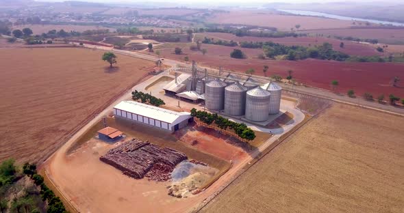 Grain storage silos on agricultural land, orbiting aerial shot