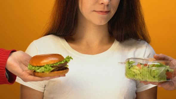 Smiling Lady Choosing Green Salad Instead of Hamburger, Healthy Diet Concept