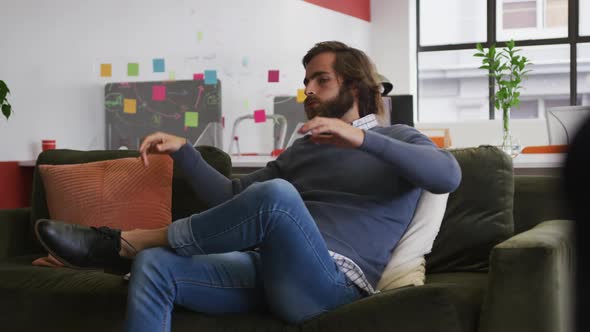 Caucasian businessman sitting on couch and resting in modern office