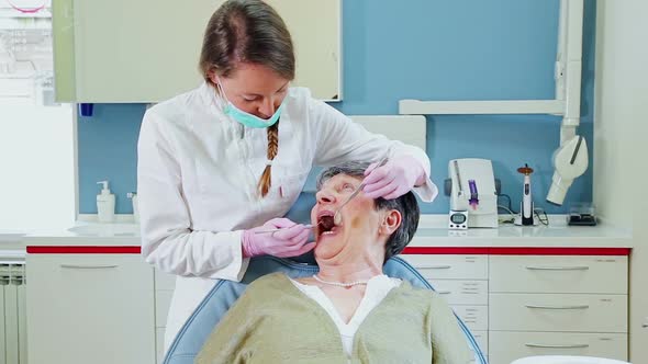 Female dentist doing dental treatment to elderly patient