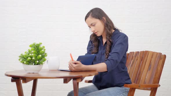 Indian girl writing a book at a cafe