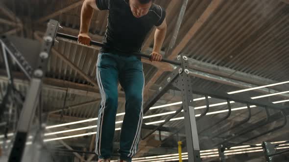 Medium Shot of an Athlete Jumping on a Horizontal Bar and Doing a Flip Up Lift