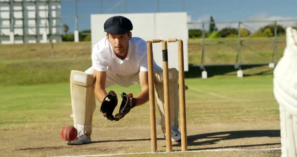 Wicket keeper collecting cricket ball behind stumps during match