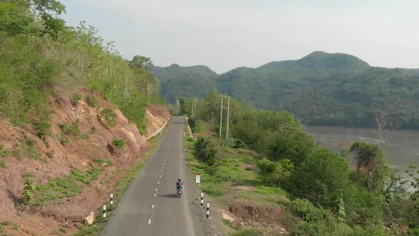 Aerial view of Motorcyclist on road next to Mekong River, Laos 