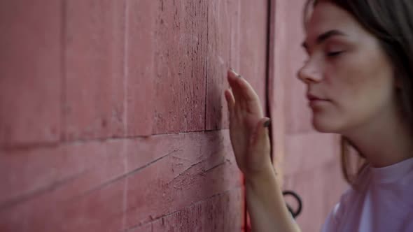 Closeup of Young Caucasian Woman Knocking in Red Wooden Door Outdoors