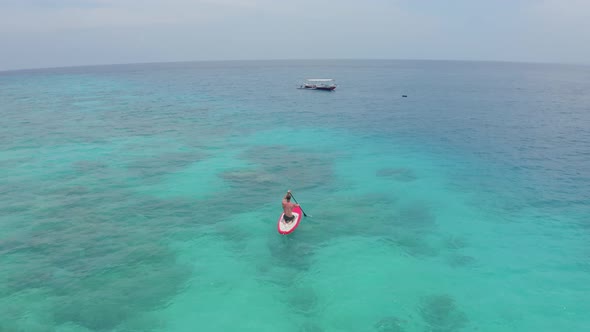 Aerial View of Young Man Tourist Floats on Red Boat on Clear Azure Waters