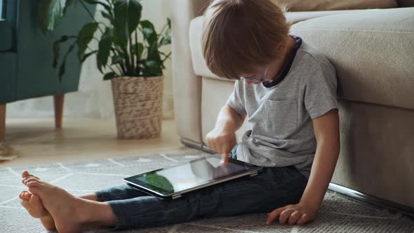 Child Using Tablet Sitting on the Floor at Home Finger Drawing Early Child Development